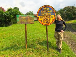 Posing at Kibati ranger station with the bullet-ridden signpost of Virunga National Park