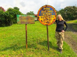 Posing at Kibati ranger station with the bullet-ridden signpost of Virunga National Park